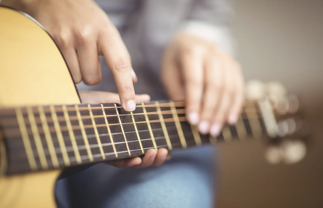 Close-up of hands playing acoustic guitar showing proper technique